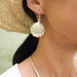 Big sterling silver seashell earring hanging from an ear.