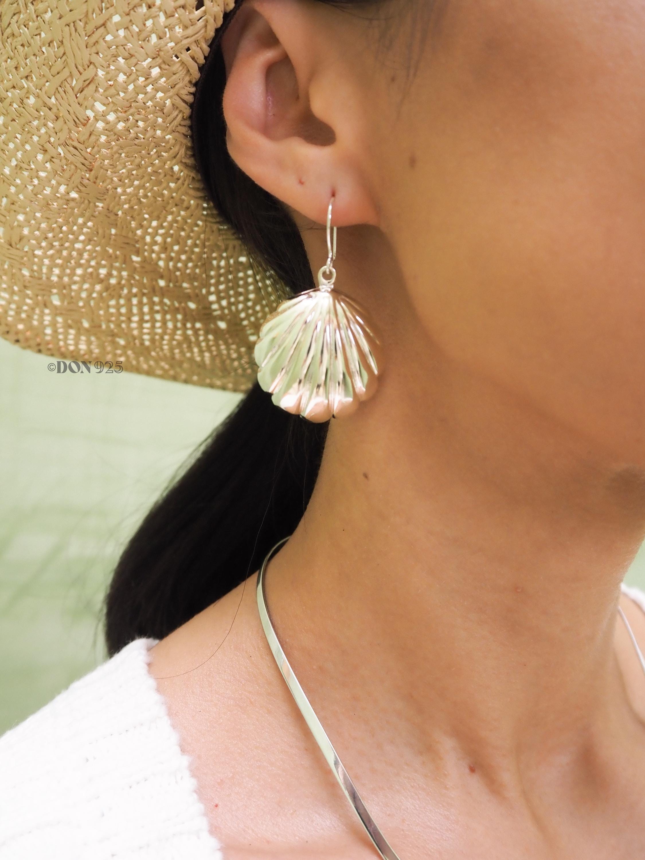 Big sterling silver seashell earring hanging from an ear.