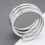 May include: A silver-colored ring with a spiral design. The ring is composed of multiple, tightly wound bands, creating a layered effect. The bands have a smooth, reflective surface, and the ring's design is modern and minimalist, suitable for everyday wear.