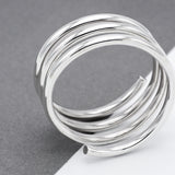 May include: A silver-colored ring with a spiral design. The ring is composed of multiple, tightly wound bands, creating a layered effect. The bands have a smooth, reflective surface, and the ring's design is modern and minimalist, suitable for everyday wear.