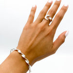 May include: A silver twisted bangle bracelet and a silver ring with a crescent moon and star design.