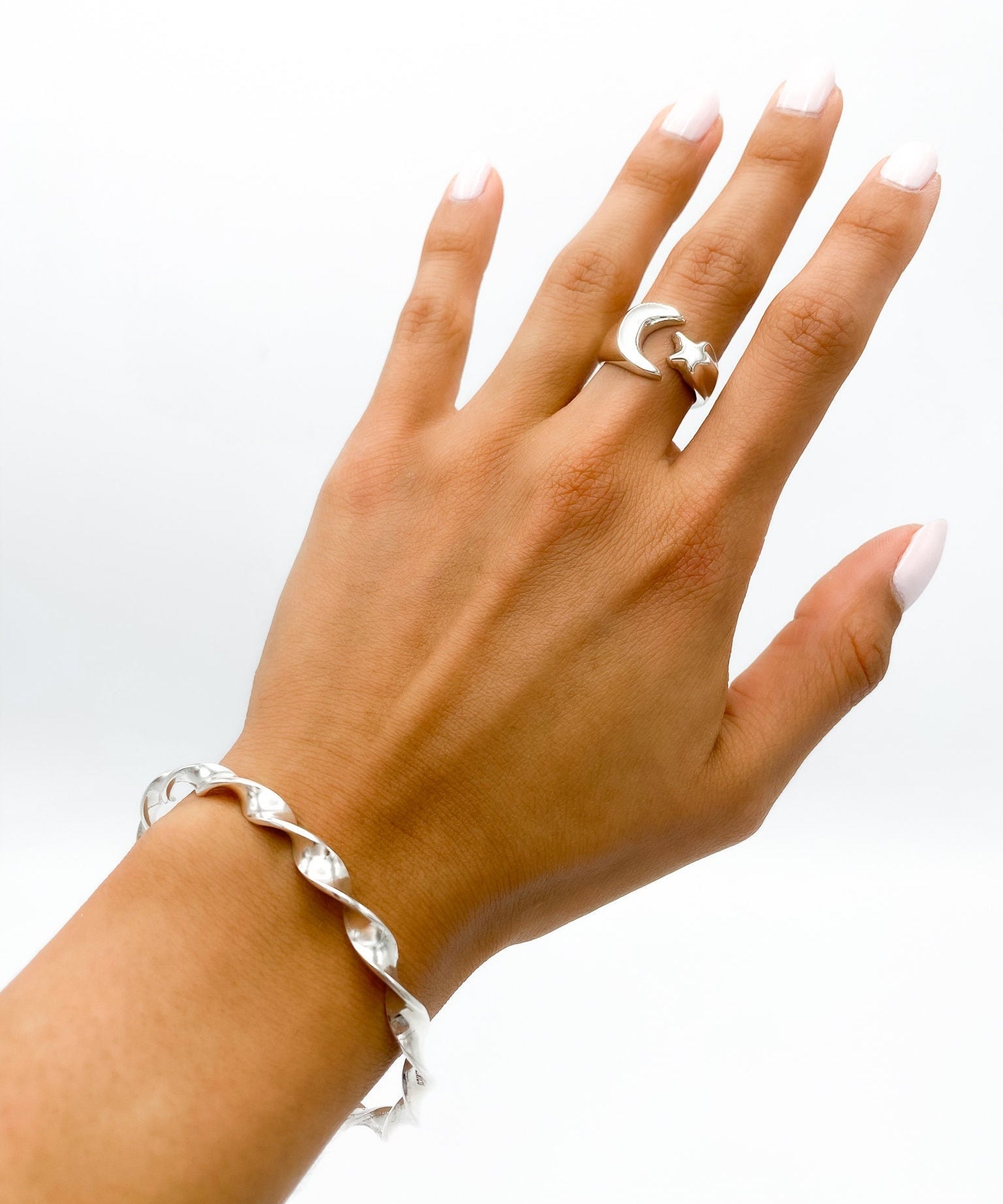 May include: A silver twisted bangle bracelet and a silver ring with a crescent moon and star design.