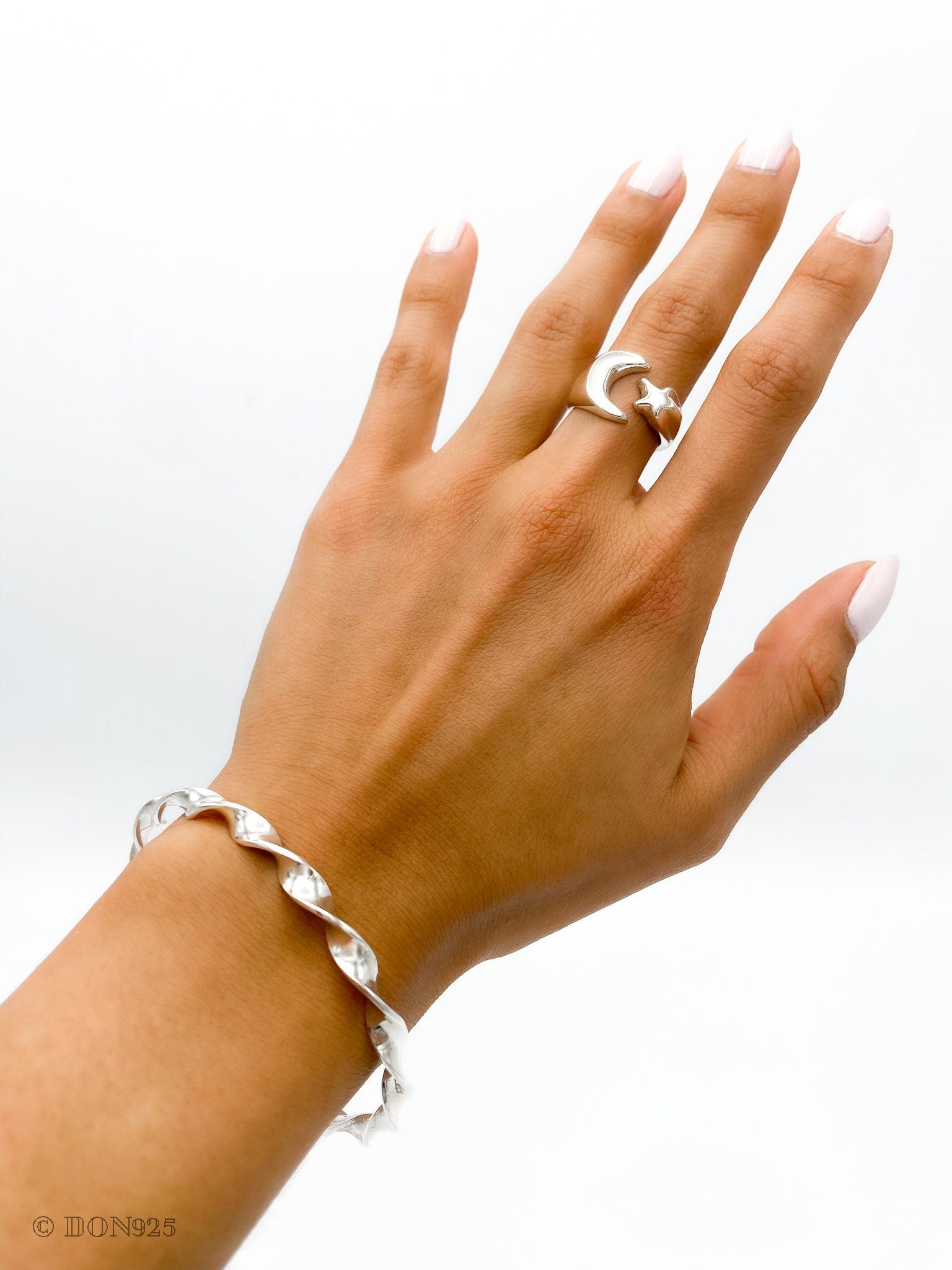 May include: A silver twisted bangle bracelet and a silver ring with a crescent moon and star design.