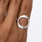 May include: A silver ring with a hammered, circular design. The ring is worn on a finger.