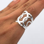 May include: A silver ring with a wide band featuring a geometric design of overlapping circles and curves.