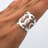May include: A silver ring with a wide band featuring a geometric design of overlapping circles and curves.