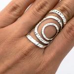 May include: A silver ring with a geometric design of overlapping circles. The ring is textured and has a modern, minimalist style.
