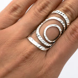 May include: A silver ring with a geometric design of overlapping circles. The ring is textured and has a modern, minimalist style.