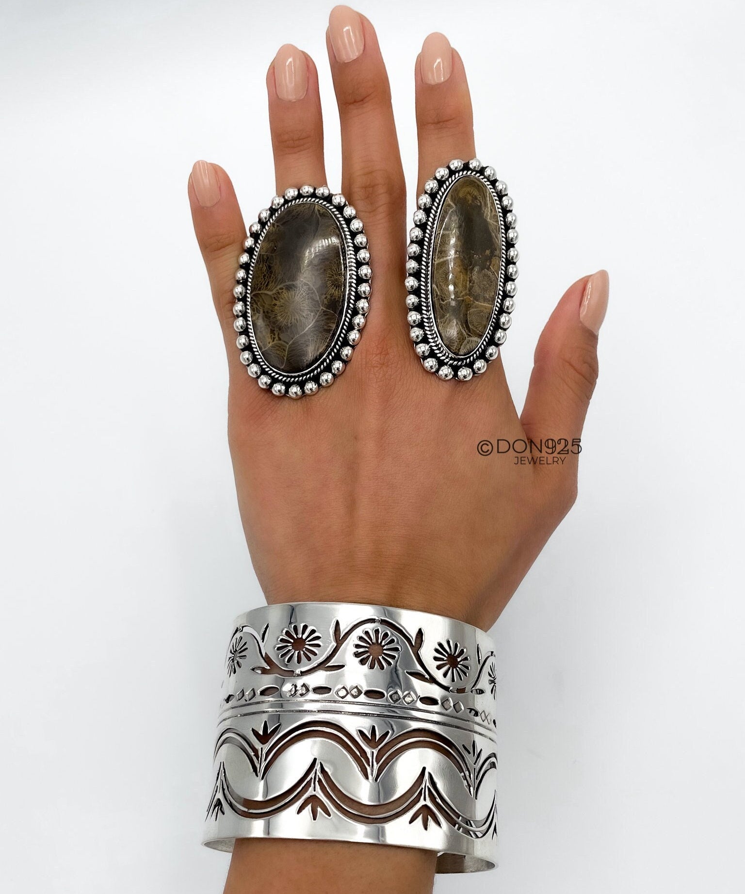 May include: Two silver rings with brown stone inlays and a silver cuff bracelet with a floral design.