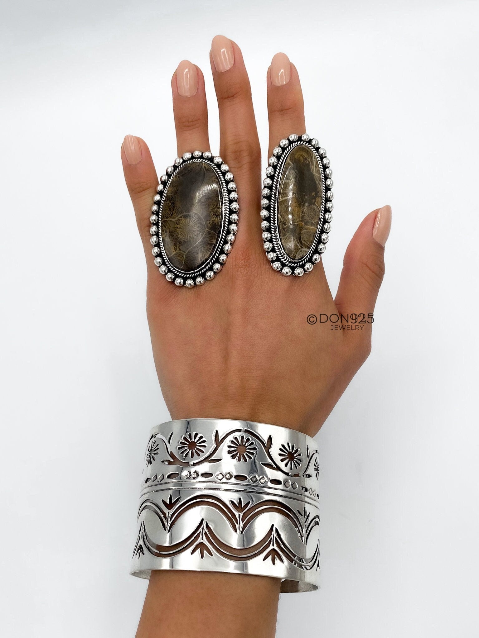 May include: Two silver rings with brown stone inlays and a silver cuff bracelet with a floral design.