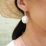 Sterling silver spiral seashell hanging from an ear