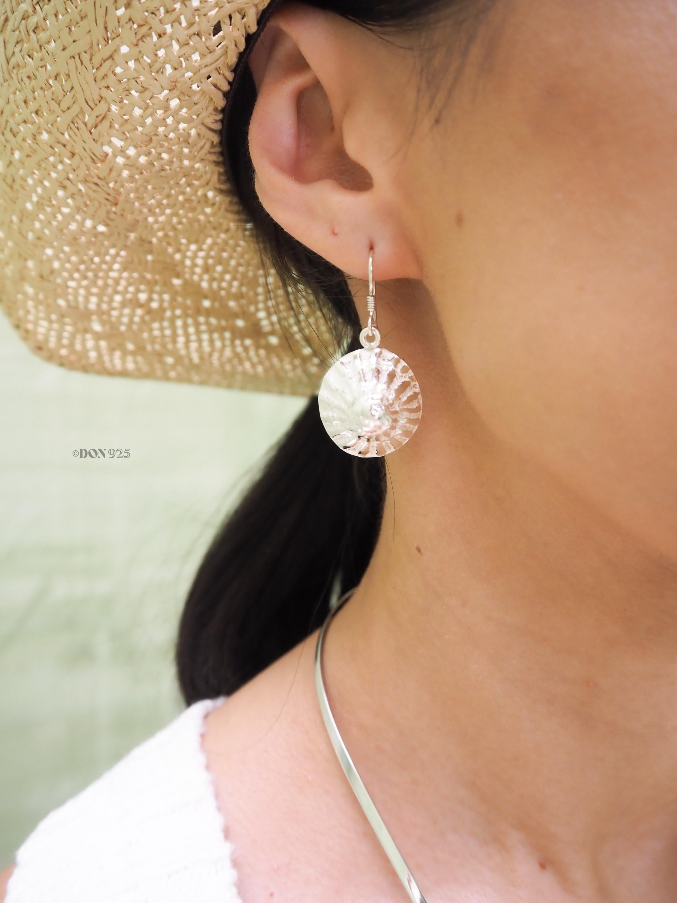 Sterling silver spiral seashell hanging from an ear