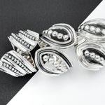 May include: Silver ring with a unique design featuring multiple overlapping curved shapes and rows of small beads.