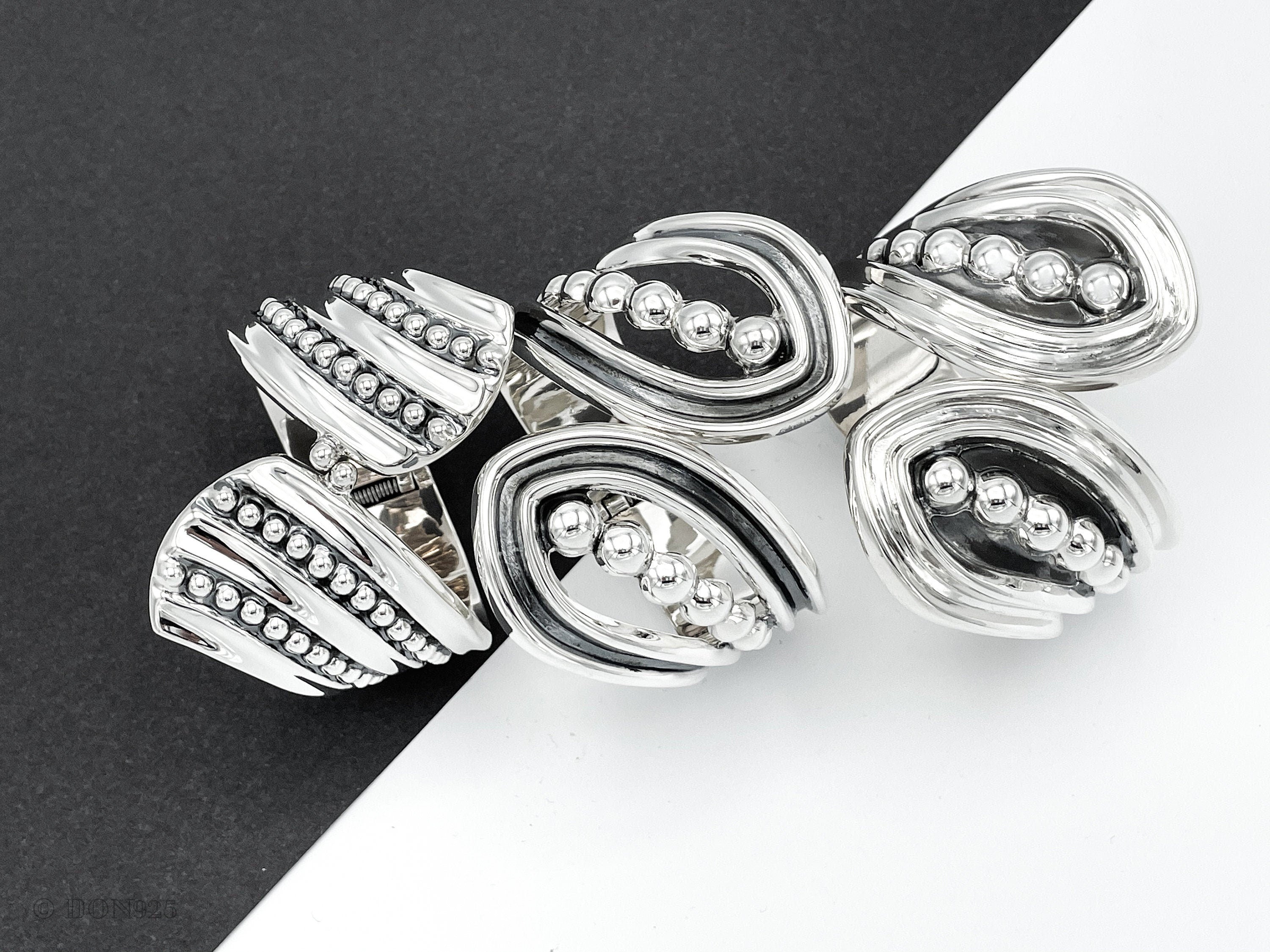 May include: Silver ring with a unique design featuring multiple overlapping curved shapes and rows of small beads.